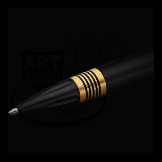 Close-up of a black ballpoint pen tip with elegant gold and black striped detailing on a dark background