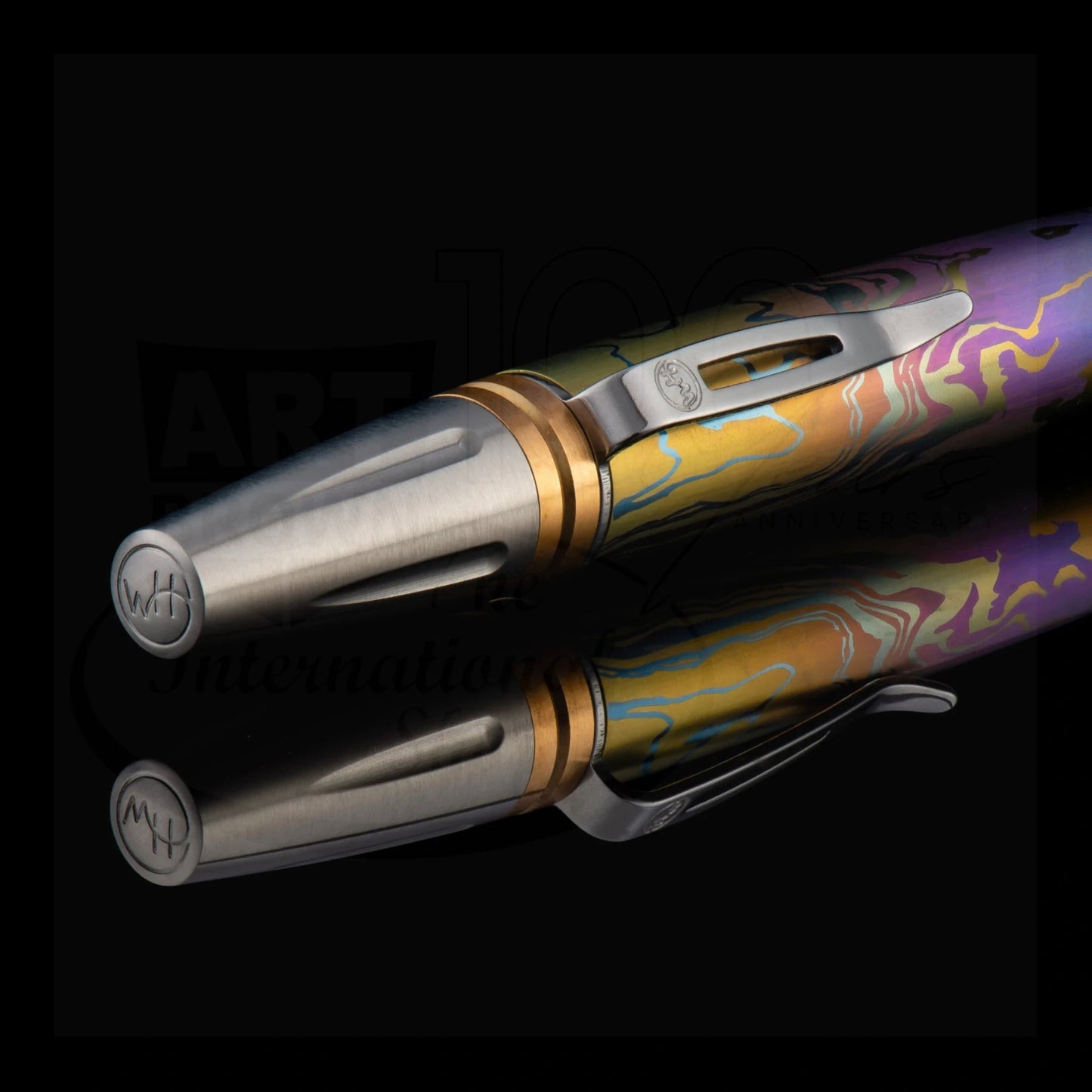 Luxury ballpoint pen with colorful marbled lacquer and brushed metal tip reflecting on black surface