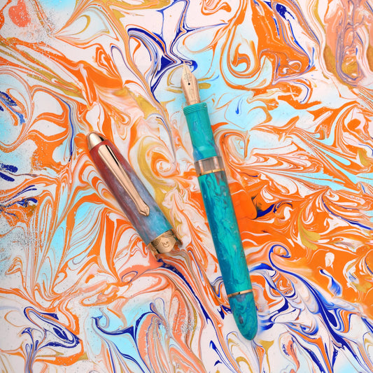 Nahvalur Horizon Dawn fountain pen in turquoise and orange pearlescent resin with rose gold trim on marbled background