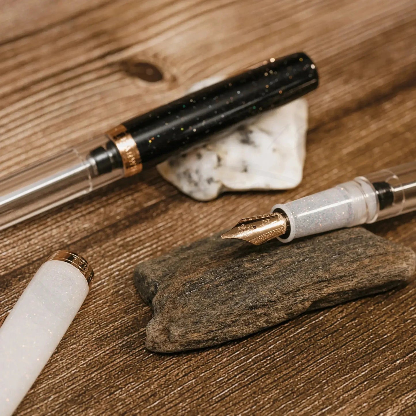 Nahvalur Original Plus Matira Quartz fountain pen in acrylic with rose gold trim, clear barrel and frosted grip on wooden surface