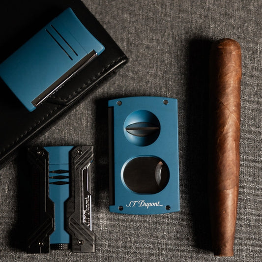 S.T. Dupont Defi XXtreme 021623 chrome petrol blue lighter with dual-flame design and sleek metal body, displayed with cigar cutter and leather case