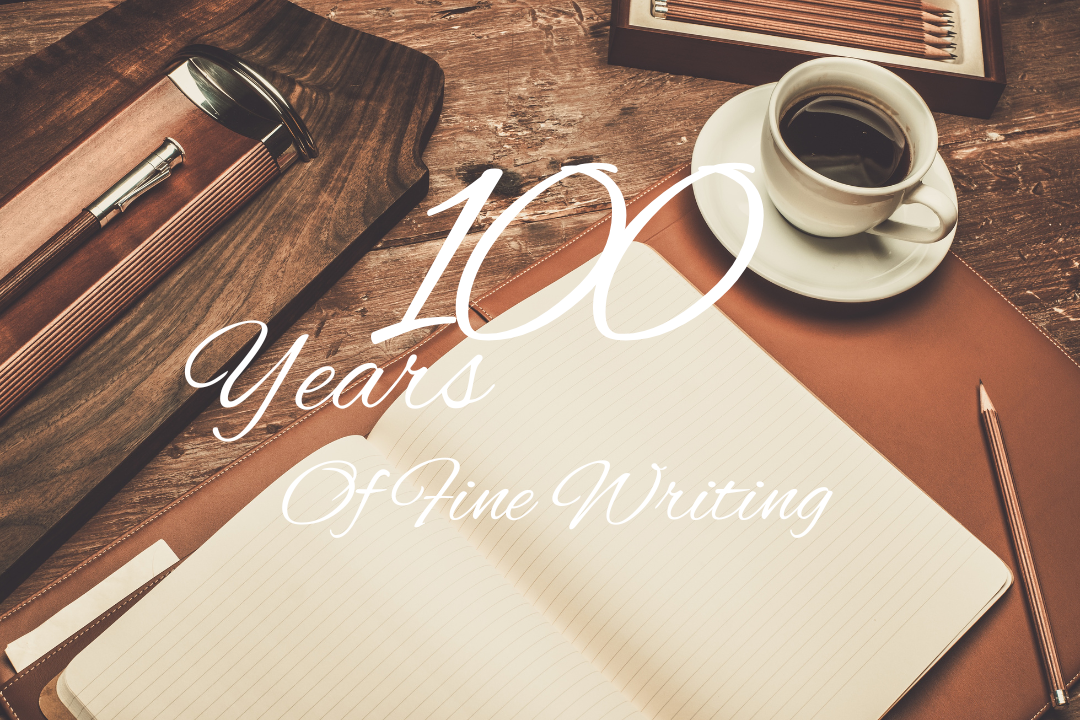 Journal, pen and pencil on a brown coffee table with the slogan "100 years of fine writing"