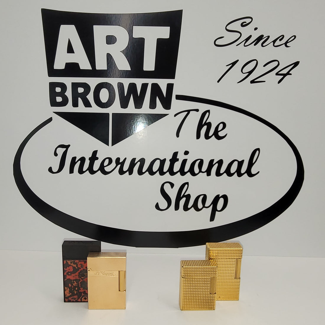 S.T. Dupont ligne 1 and ligne 2 lighters in front of Art Brown logo on white background.