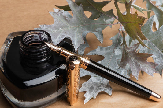 S.T. Dupont Liberte fountain pen in black sitting aside inkwell.