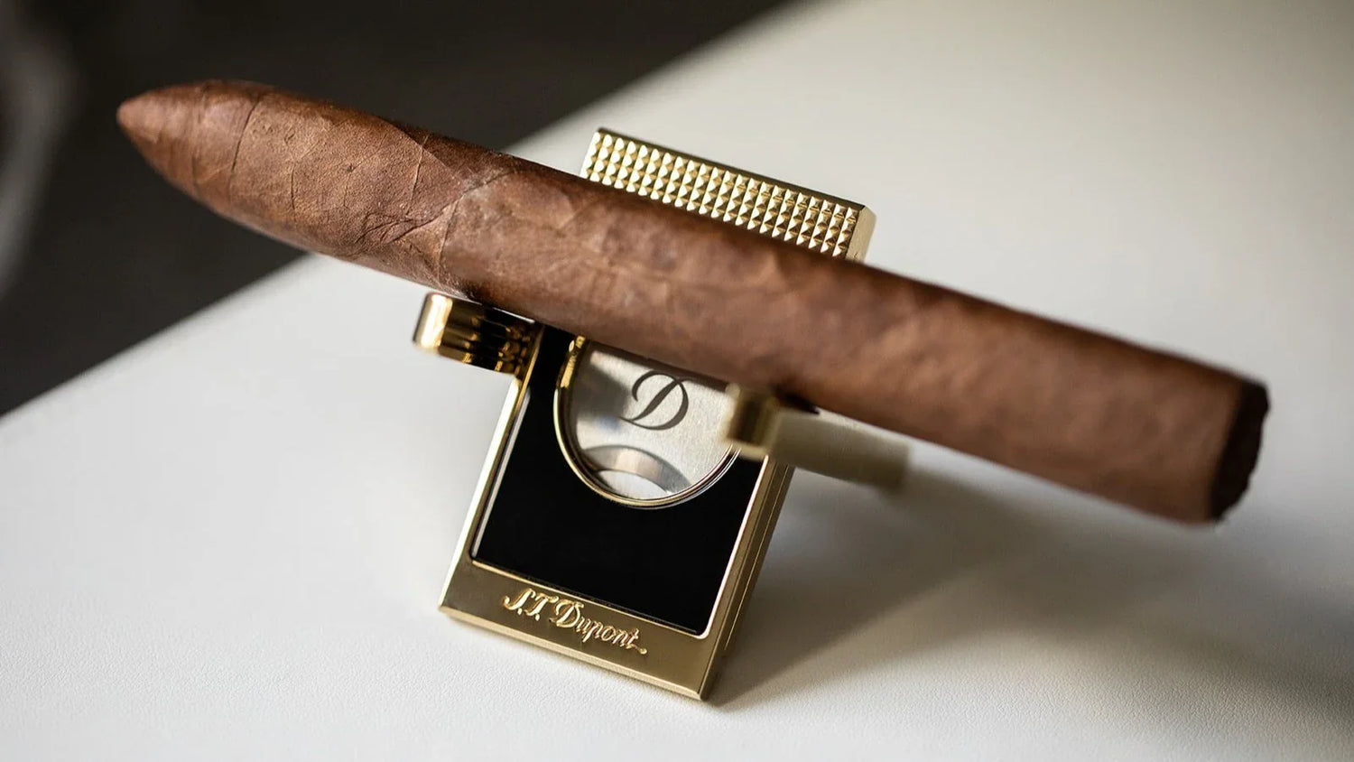 S.T. Dupont cigar cutter with cigar stand in black lacquer and gold with a cigar resting on top