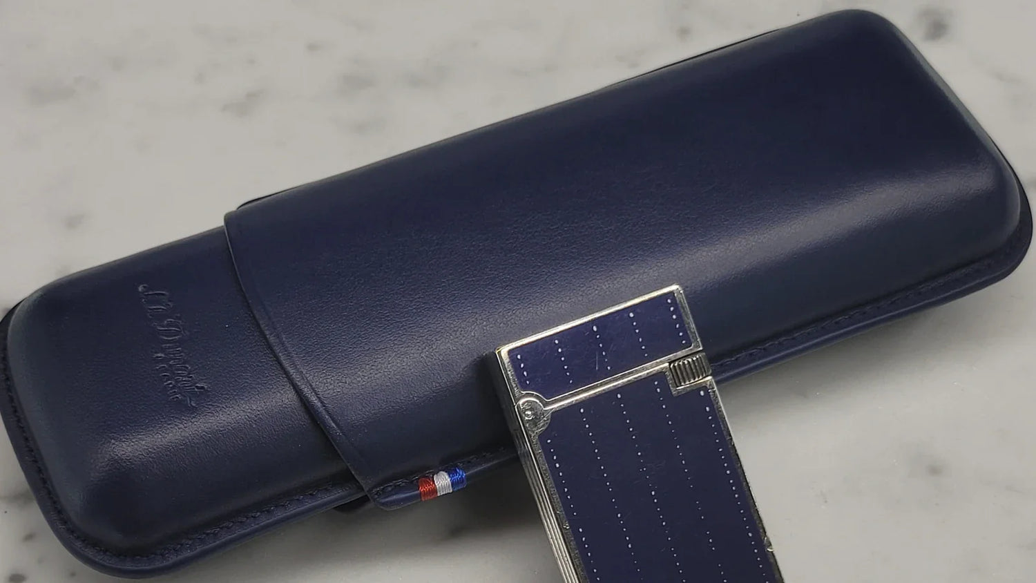 Blue leather cigar case for 2 cigars on marble backdrop with S.T. Dupont lighter