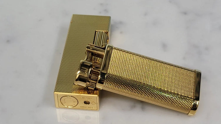 Dunhill Unique and rollagas lighter in gold barley grain on a white marble background