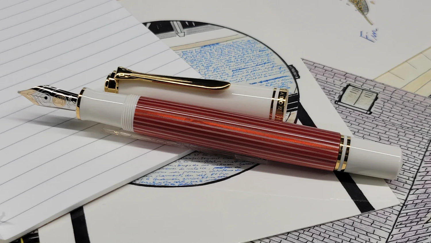 Pelikan m600 special edition red and white fountain pen with gold nib sitting on stop of stationary set