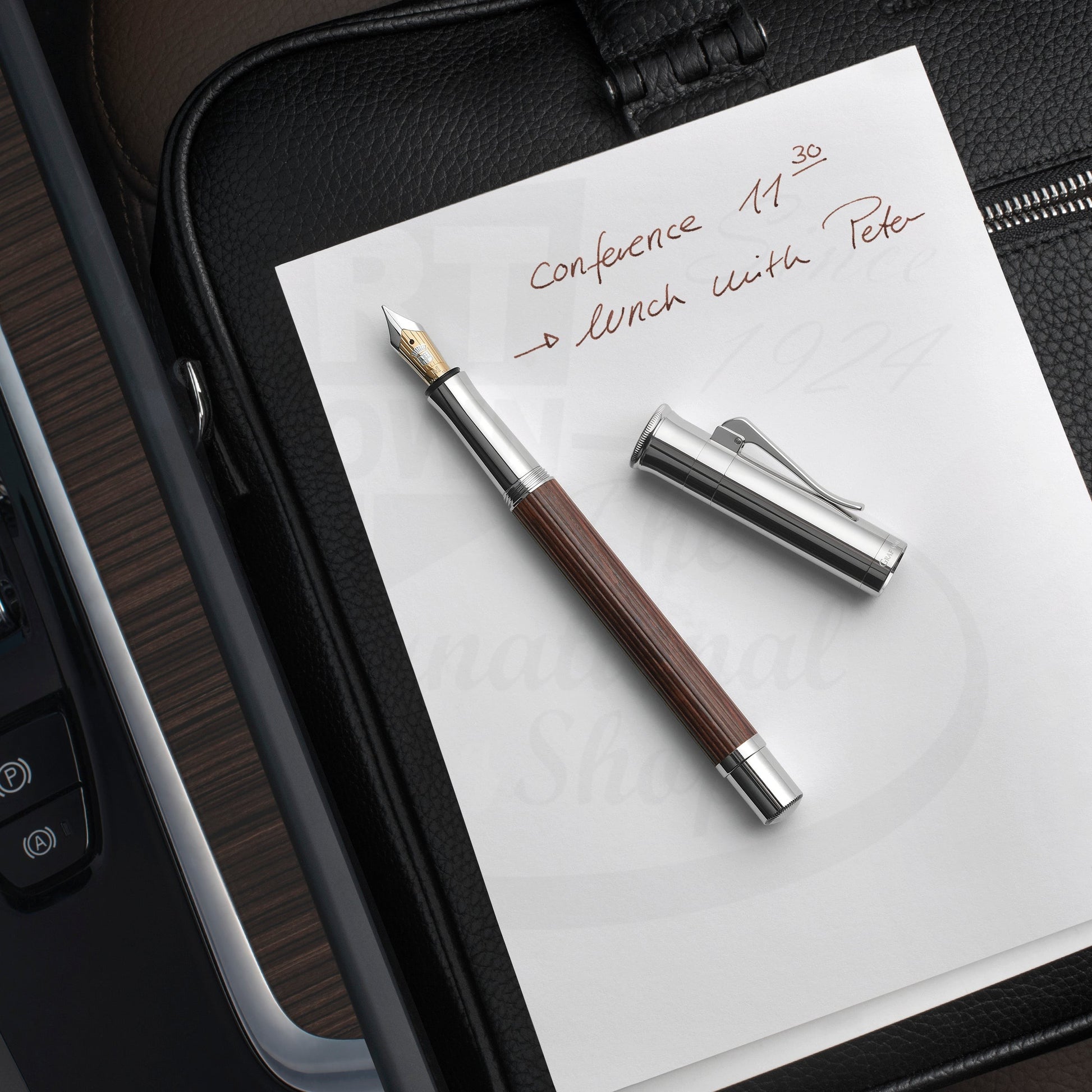 Graf von Faber-Castell Classic Grenadilla Fountain Pen with silver cap and brown wood barrel on white paper writing