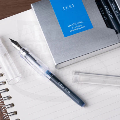 Pilot Iroshizuku 6-pack cartridges in silver box with transparent fountain pen, plastic cartridge holder on lined notebook paper