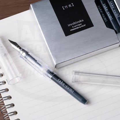 Pilot Iroshizuku fountain pen ink cartridge 6-pack in silver packaging, displayed with clear demonstrator fountain pen on lined notebook paper