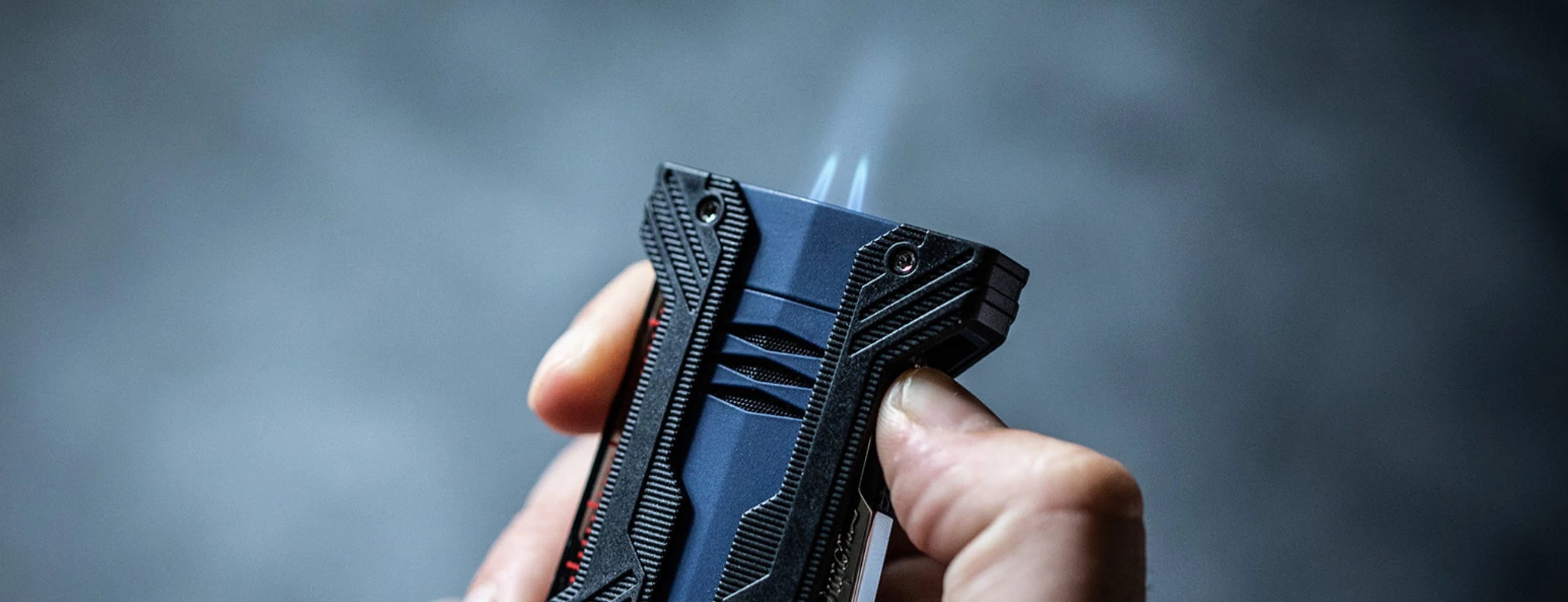 S.T. Dupont Defi Extreme collection matte blue and black finishes close-up view with dual torch flames and reinforced bumper design