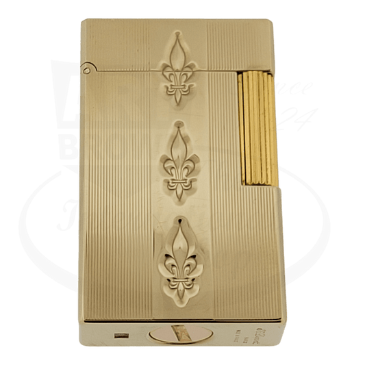 S.T. Dupont Ligne 1 gold-plated brass petrol lighter featuring three embossed fleur-de-lis motifs and vertical ribbed texture with golden side roller ignition