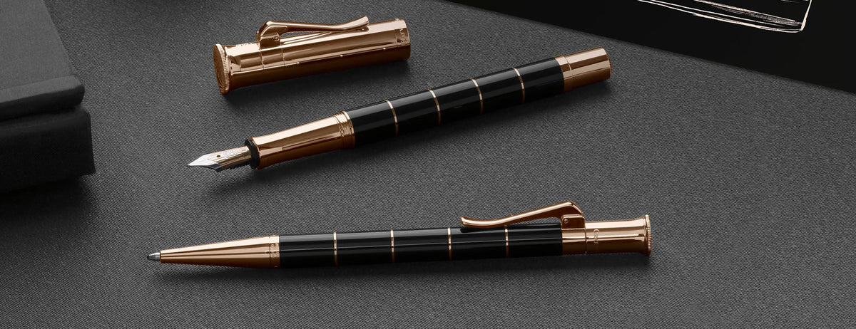 Graf von Faber-Castell Classic Anello fountain and ballpoint pens with black resin and rose gold accents on leather desk top