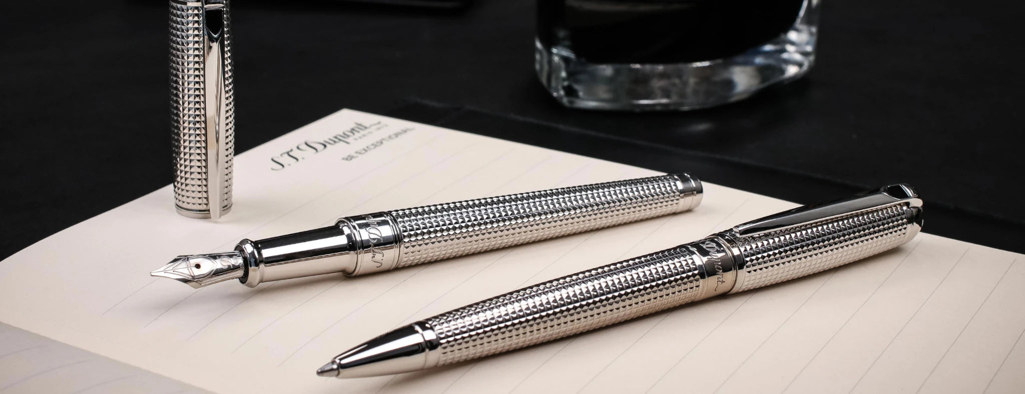 S.T. Dupont Line D ballpoint and fountain in palladium with diamond head guilloche, displayed on S.T. Dupont notepad