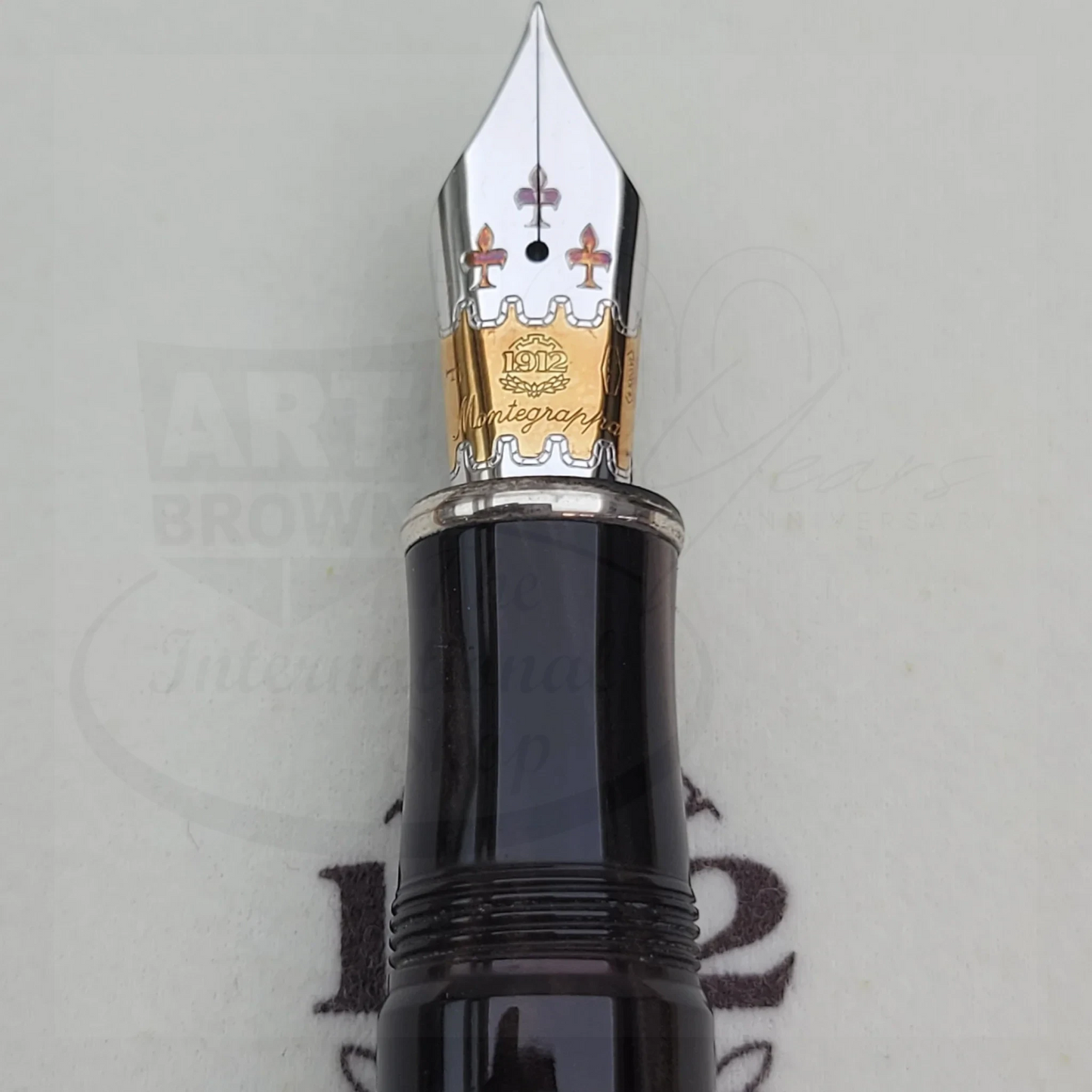 Close-up of a luxury fountain pen nib with intricate gold and silver detailing on a black body.
