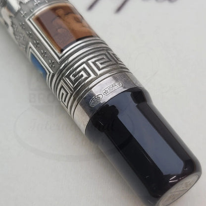 Close-up of a luxury fountain pen nib section with intricate silver guilloche detailing and a dark glossy grip.
