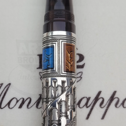 Close-up of a luxury fountain pen with intricate silver guilloche and colored enamel details on the barrel.