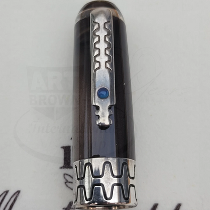 Close-up of a fountain pen cap with intricate silver clip and patterned band featuring a blue gemstone detail.