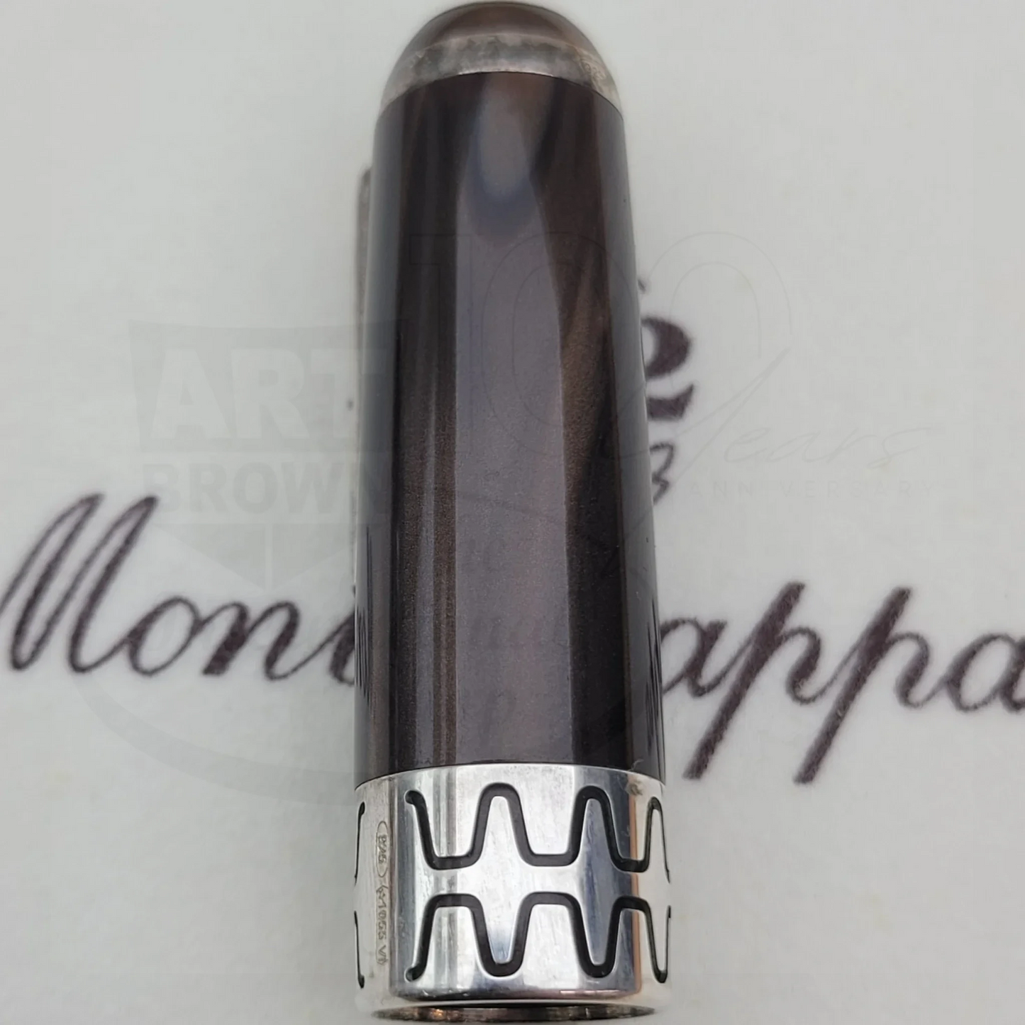 Close-up of a dark luxury fountain pen cap with silver decorative band and subtle wood grain finish.