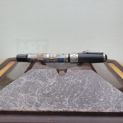 Luxury fountain pen with intricate engravings and silver accents resting on a textured display stand.