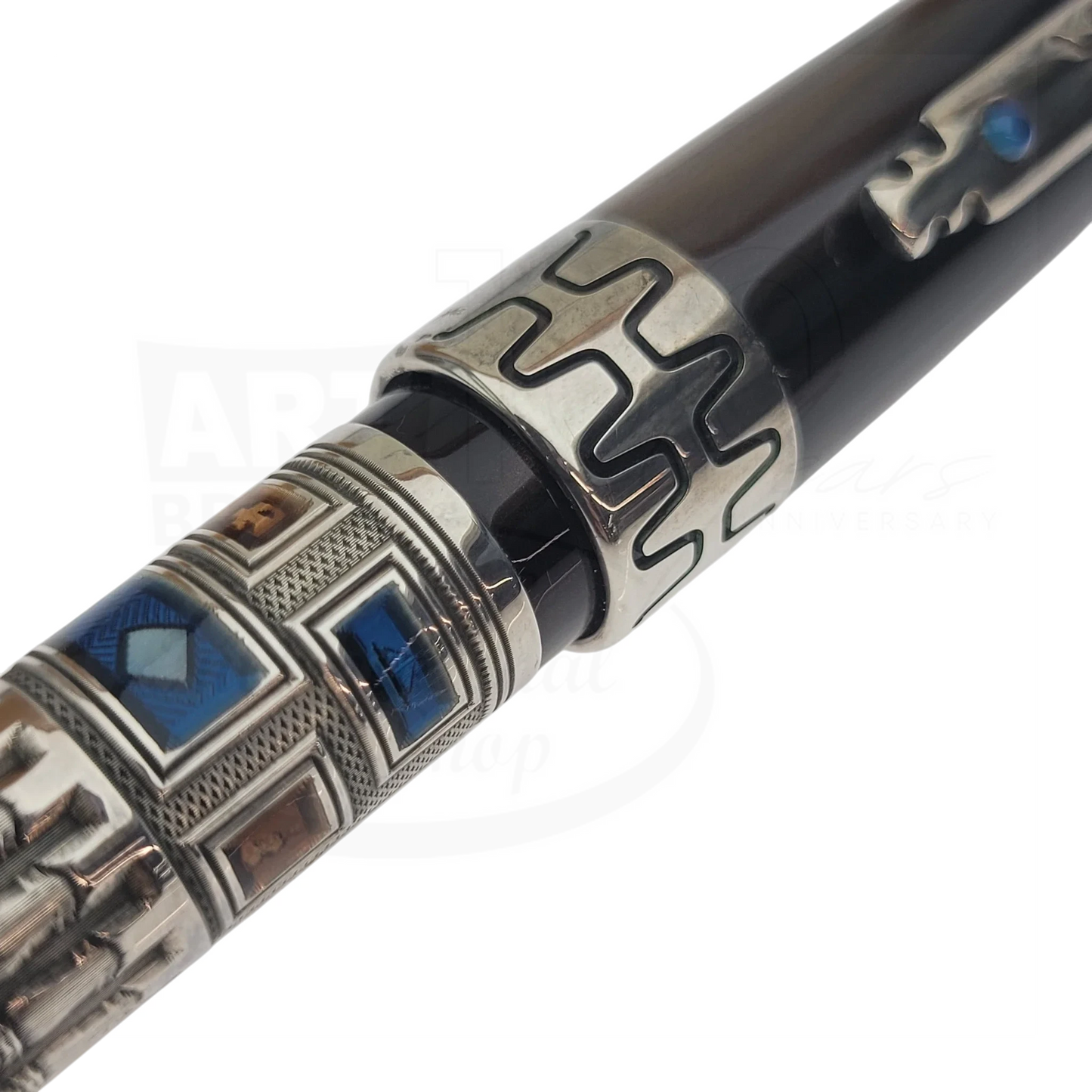 Close-up of a luxury fountain pen with intricate metallic and blue enamel detailing on the barrel and cap ring.