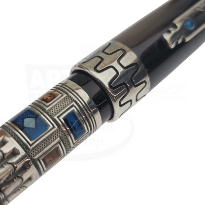 Close-up of a luxury fountain pen with intricate metallic and blue enamel detailing on the barrel and cap ring.