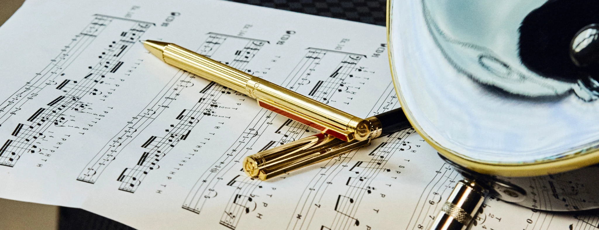 S.T. Dupont New Classique ballpoint pens in gold with red lacquer, and gold with black lacquer, on page of sheet music 
