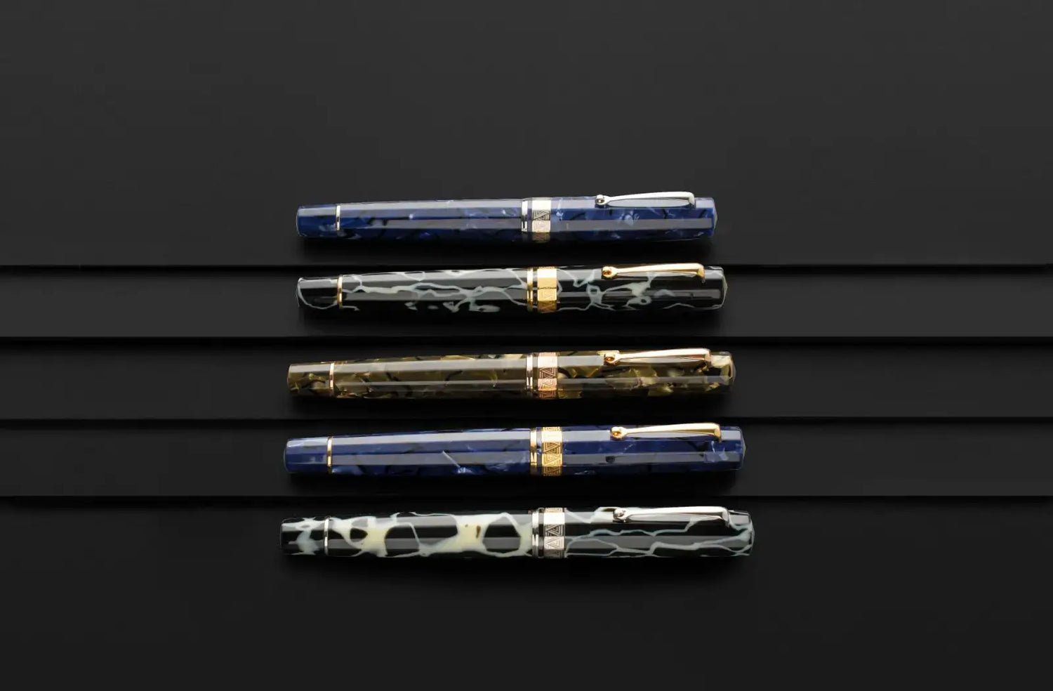 OMAS Paragon celluloid fountain pens displayed on a black backdrop.